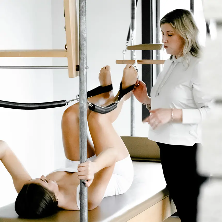 Pilates teacher providing cues to a female client on the Cadillac during a introductory private session