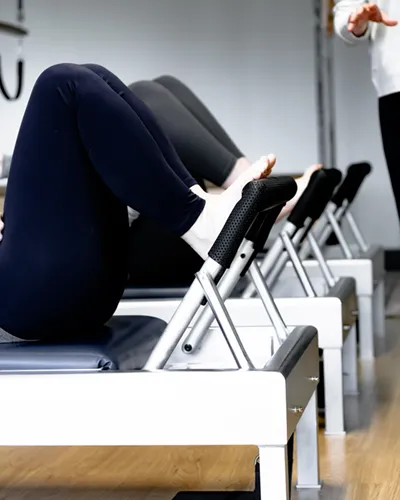 Pilates instructor teaching a group of women on the Reformers during a Mixed Equipment Pilates class in Golden Valley.